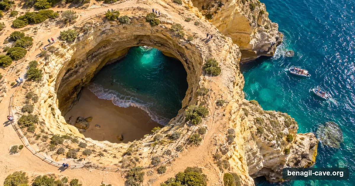 Benagil Cave from above: the round skylight in the clifftop, turquoise water and the hidden beach below, and tour boats waiting outside the western arch